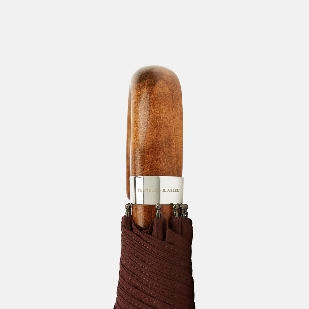 A fully opened Turnbull & Asser Burgundy Telescopic Umbrella with a brown maple crook handle, displayed against a plain white background—a refined men's accessory.