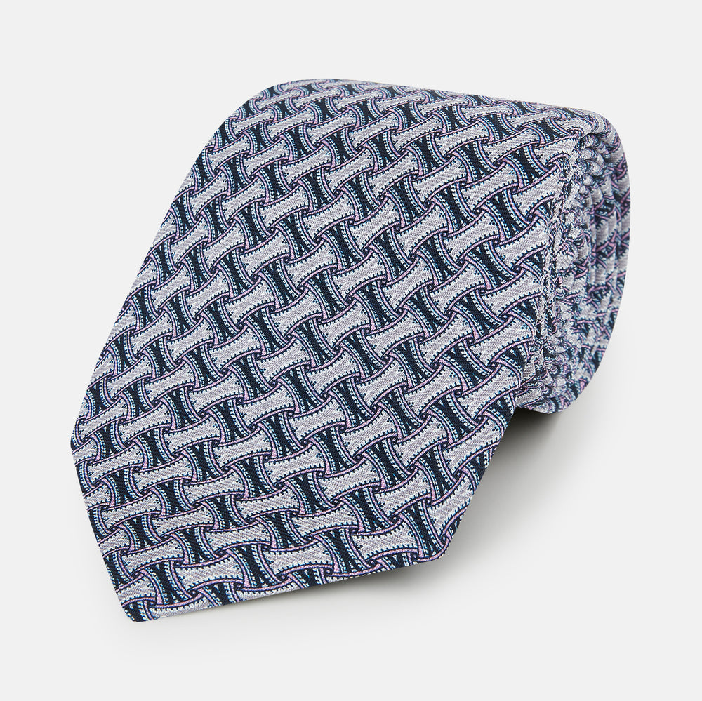 The Turnbull & Asser Navy and Pink Weave-Patterned Printed Silk Tie is shown rolled up on a white background, featuring a stylish geometric design.