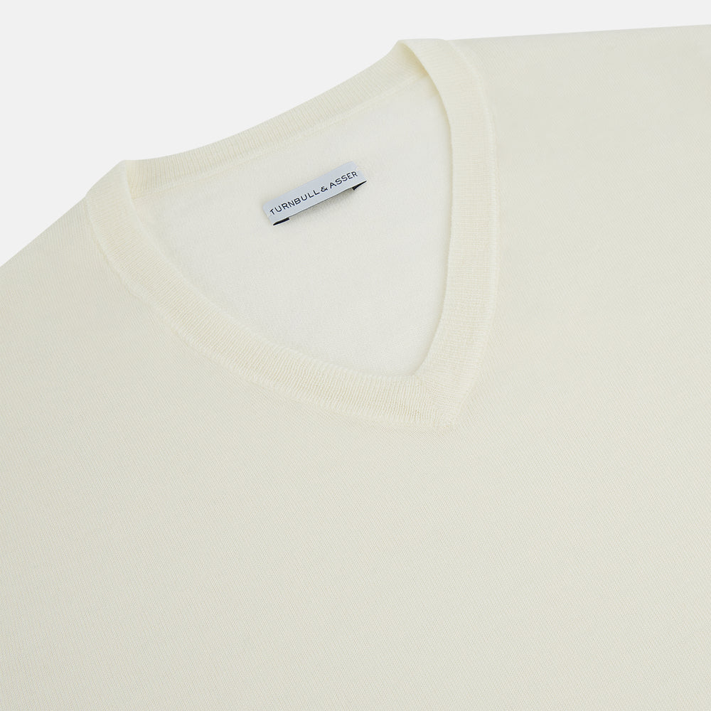 The Turnbull & Asser Cream Fine Merino V-Neck Jumper features long sleeves and classic styling, displayed against a white background.