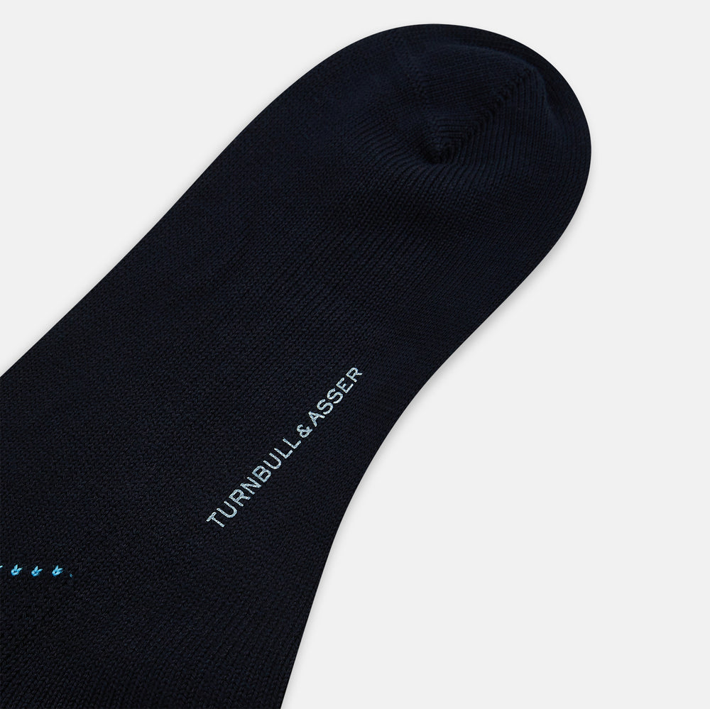 The Turnbull & Asser Navy Check Mid-Length Sock, crafted from ultra-soft cotton, features a blue and light blue argyle pattern with diamond shapes and dotted lines, and is showcased against a plain white background.
