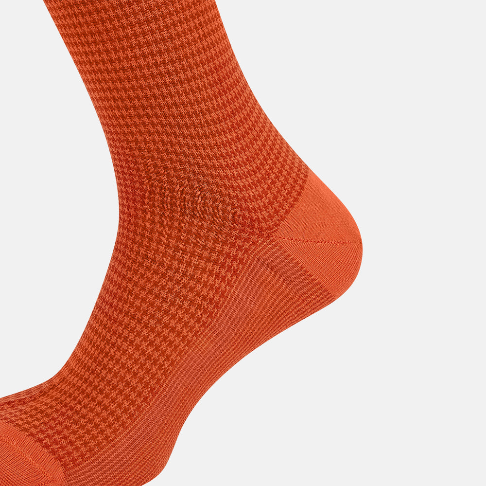 The Orange Houndstooth Long Sock by Turnbull & Asser is a single, knee-high sock featuring a ribbed cuff and textured houndstooth pattern, crafted from luxurious mercerised Egyptian cotton and shown on a white background.