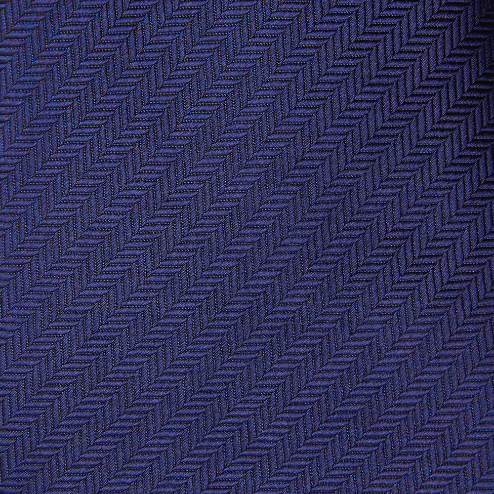 The PLAIN HERRINGBONE NAVY TIE by Turnbull & Asser, crafted from silk with a subtle pattern, is elegantly rolled and displayed against a plain white background.