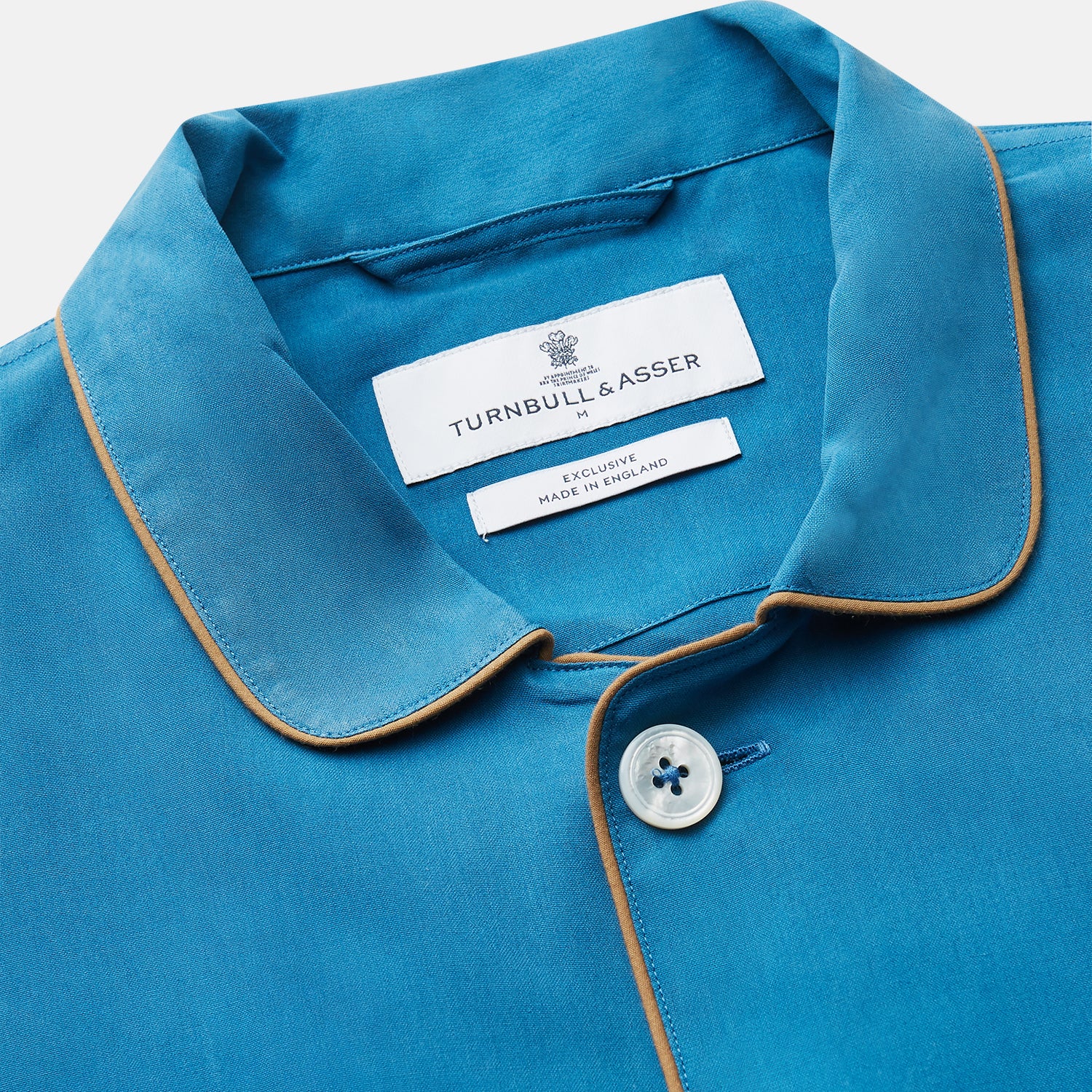 View 3 of product The Turnbull & Asser Blue Silk Hyde Pyjama Set features a modern fit with a long-sleeve button-up top, three pockets, white trim, and elastic-waist pants, all shown on a white background.