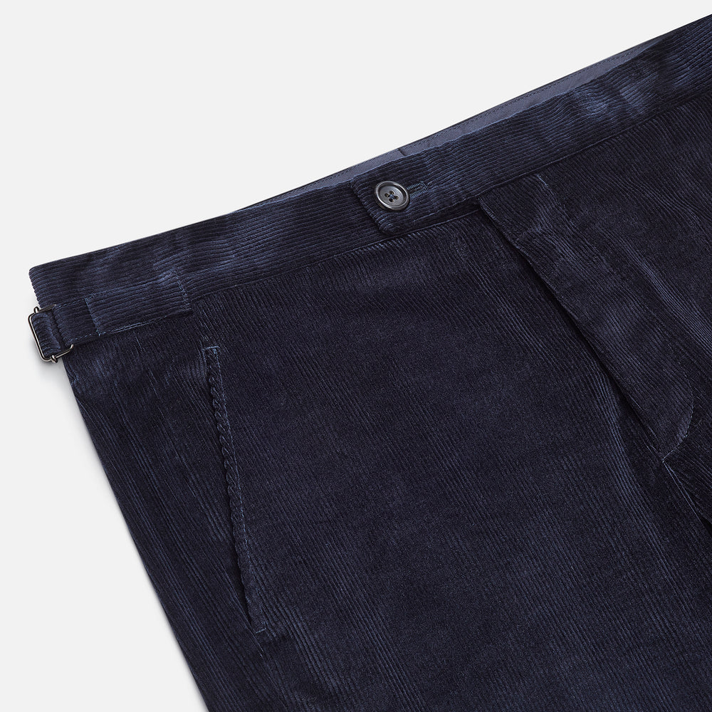 The Turnbull & Asser Navy Corduroy Henry Trousers are tailored fit with a straight-leg cut, made from a wool-cotton blend, and feature front button and zip closure, shown against a plain white background.