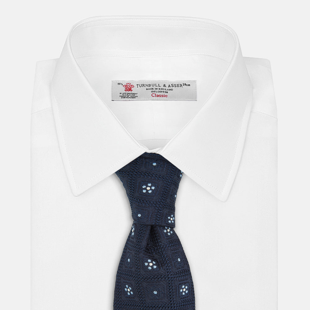 The Turnbull & Asser Jacquard Silk Circle Tie showcases a textured navy blue design with small white and light blue floral motifs—an essential accessory for refined attire.