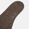 View 3 of product A single Dark Chocolate Linen Mid-Length Sock by Turnbull & Asser, ribbed and breathable, stands upright with its foot slightly raised against a plain white background.