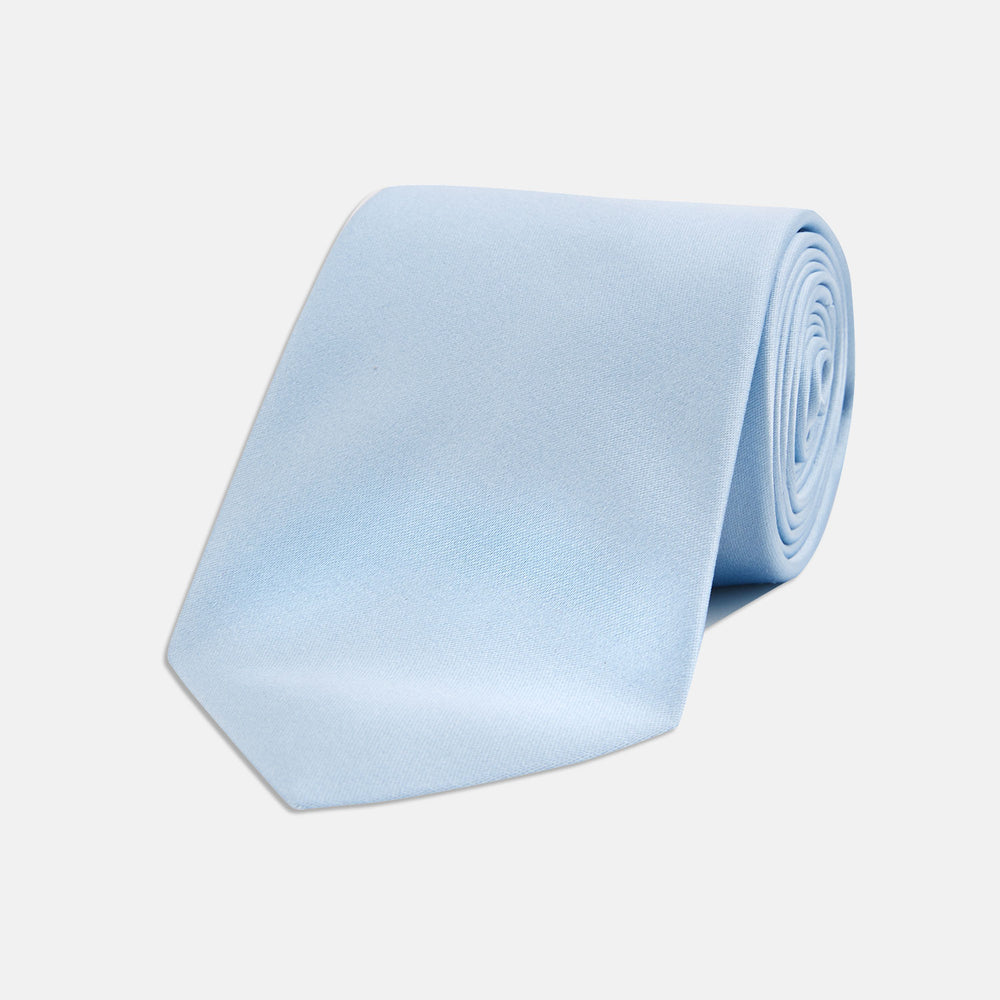 The Turnbull & Asser Plain Woven Satin Silk Tie, in light blue, is neatly rolled and displayed on a plain white background—an essential accessory for refined style.