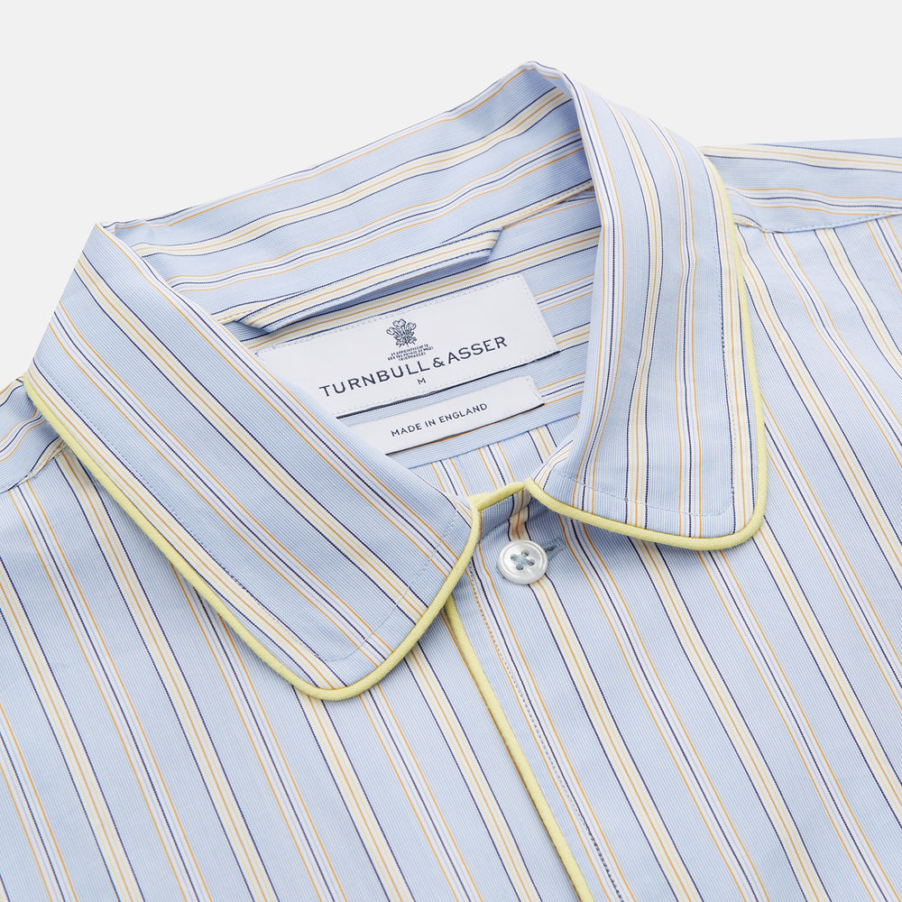 The Turnbull & Asser Blue and Yellow Stripe Poplin Cotton Nightshirt features light blue and yellow vertical stripes, long sleeves, a classic collar, single chest pocket, rounded hem, and is displayed flat on a white background.