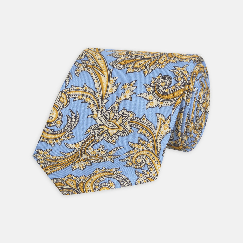 The Turnbull & Asser GGT92000 3062 06 OS is a rolled-up necktie with an intricate blue and yellow paisley pattern on a light blue background—a stylish accessory for any wardrobe.