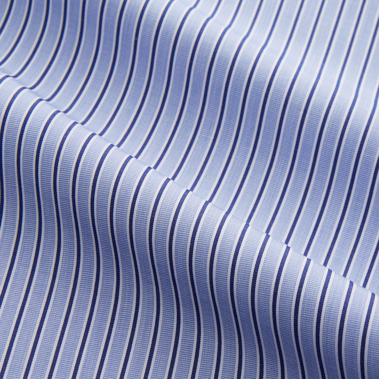 View 2 of product The Blue and Navy Halo Stripe Cotton Sussex Nightshirt by Turnbull & Asser features long sleeves, a collar, button-down front, chest pocket, curved hem, and brown piping for a classic luxury sleepwear style.
