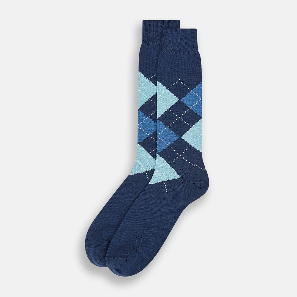 The Azzurro Wool Check Mid-Length Socks by Turnbull & Asser are navy blue with a ribbed cuff, featuring an argyle pattern in light blue, teal, and navy with white accents. Displayed upright against a plain white background.