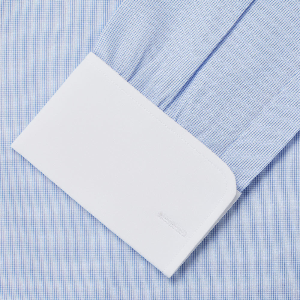 The Turnbull & Asser Micro Blue Check with White Collar and Cuff Shirt, a light blue long-sleeve style, features contrasting white collar and cuffs, buttoned down the front and laid flat on a white background.