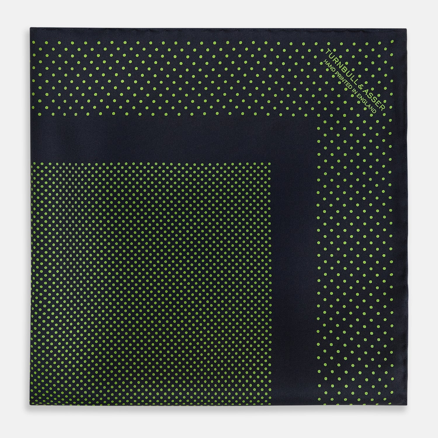 View 3 of product The Turnbull & Asser Navy and Kelly Green Dot Silk Pocket Square features small green dots on navy silk and a folded corner displaying the reverse—an elegant, handmade accessory perfect for enhancing any formal attire.