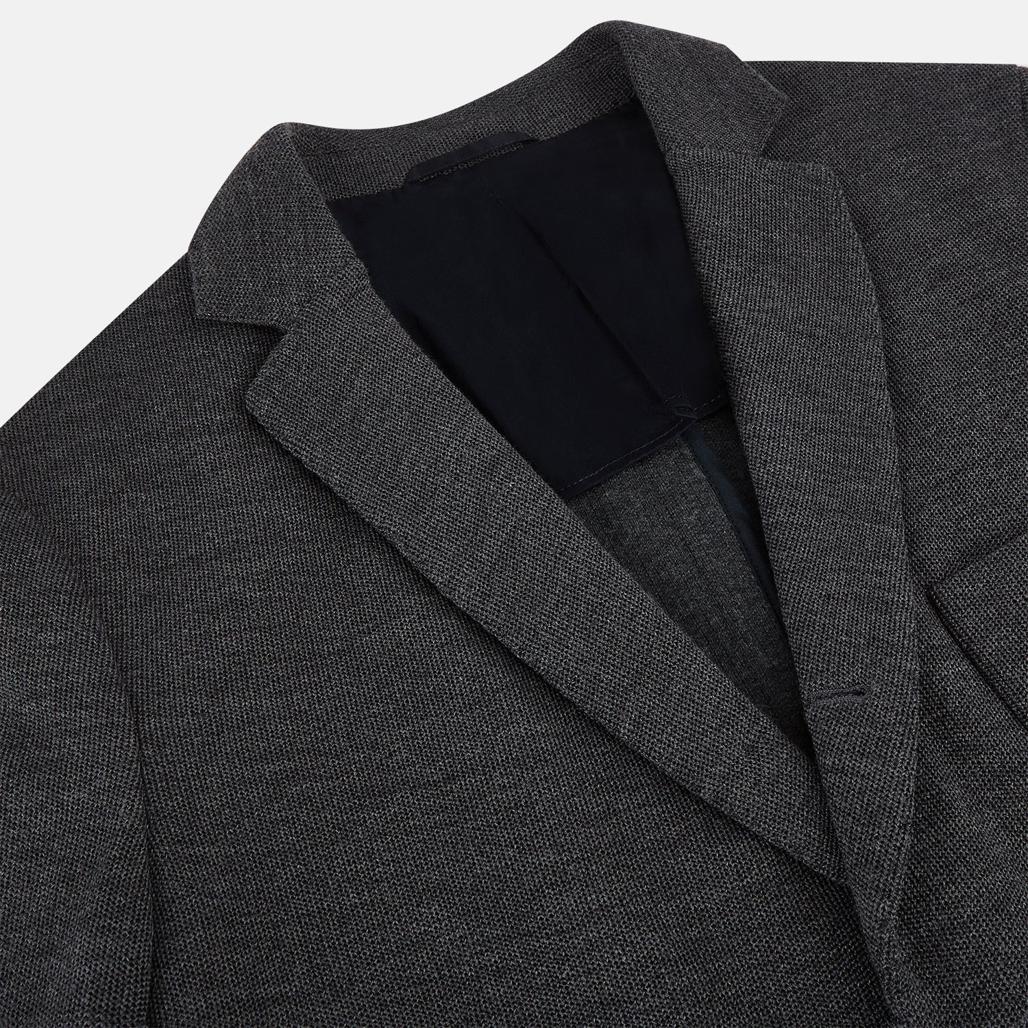 Image 2 of product The Turnbull & Asser Graphite Knitted Oxford Blazer for men features a dark gray hue, two buttons, notched lapels, and three front pockets—a modern British-inspired piece styled elegantly against a light background.
