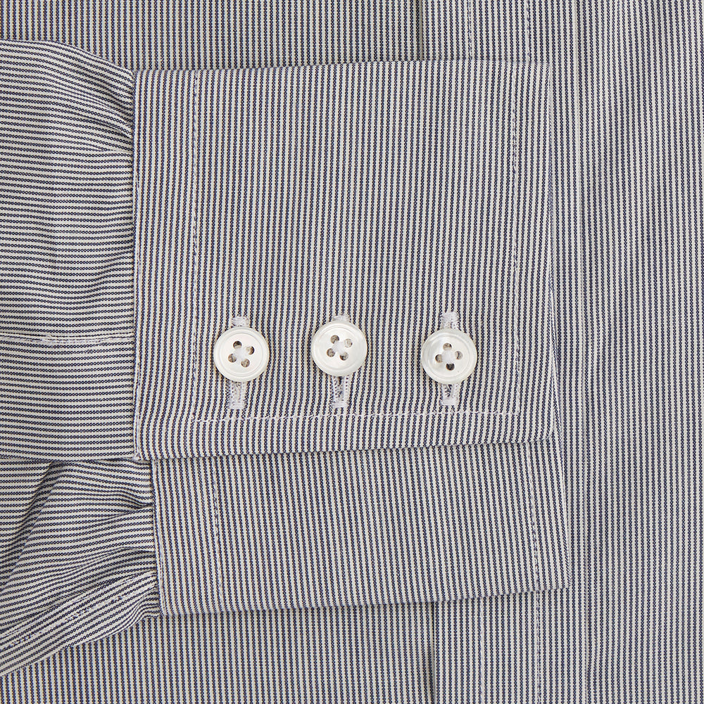 The Turnbull & Asser Navy Fine Stripe Mayfair Shirt, a long-sleeve, button-up with a classic collar, features fine navy stripes and white buttons, shown laid flat on a white background.