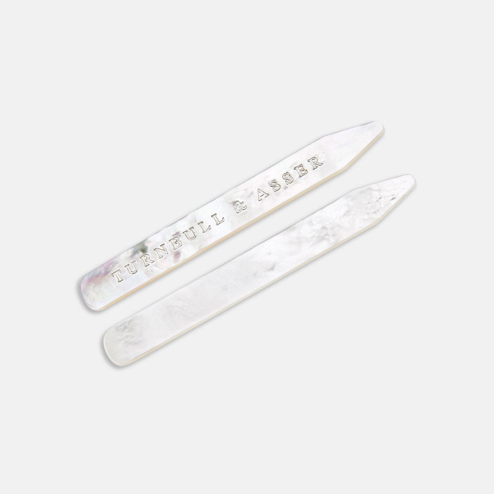 Two Turnbull & Asser Mother-of-Pearl Collar Stays, one engraved with the brand name, are displayed side by side on a plain light background.