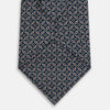 View 3 of product The Turnbull & Asser Navy Mélange Paisley and Square Print Silk Tie is crafted from fine silk, showcasing a repeating paisley and square pattern in blue tones, elegantly rolled for display on a white background.