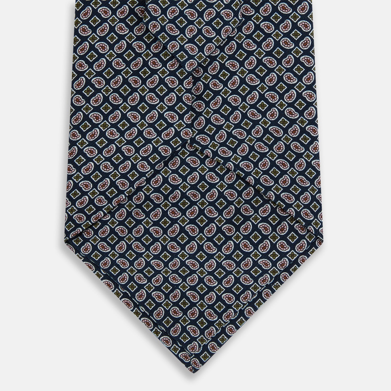 View 3 of product The Turnbull & Asser Navy Mélange Paisley and Square Print Silk Tie is crafted from fine silk, showcasing a repeating paisley and square pattern in blue tones, elegantly rolled for display on a white background.