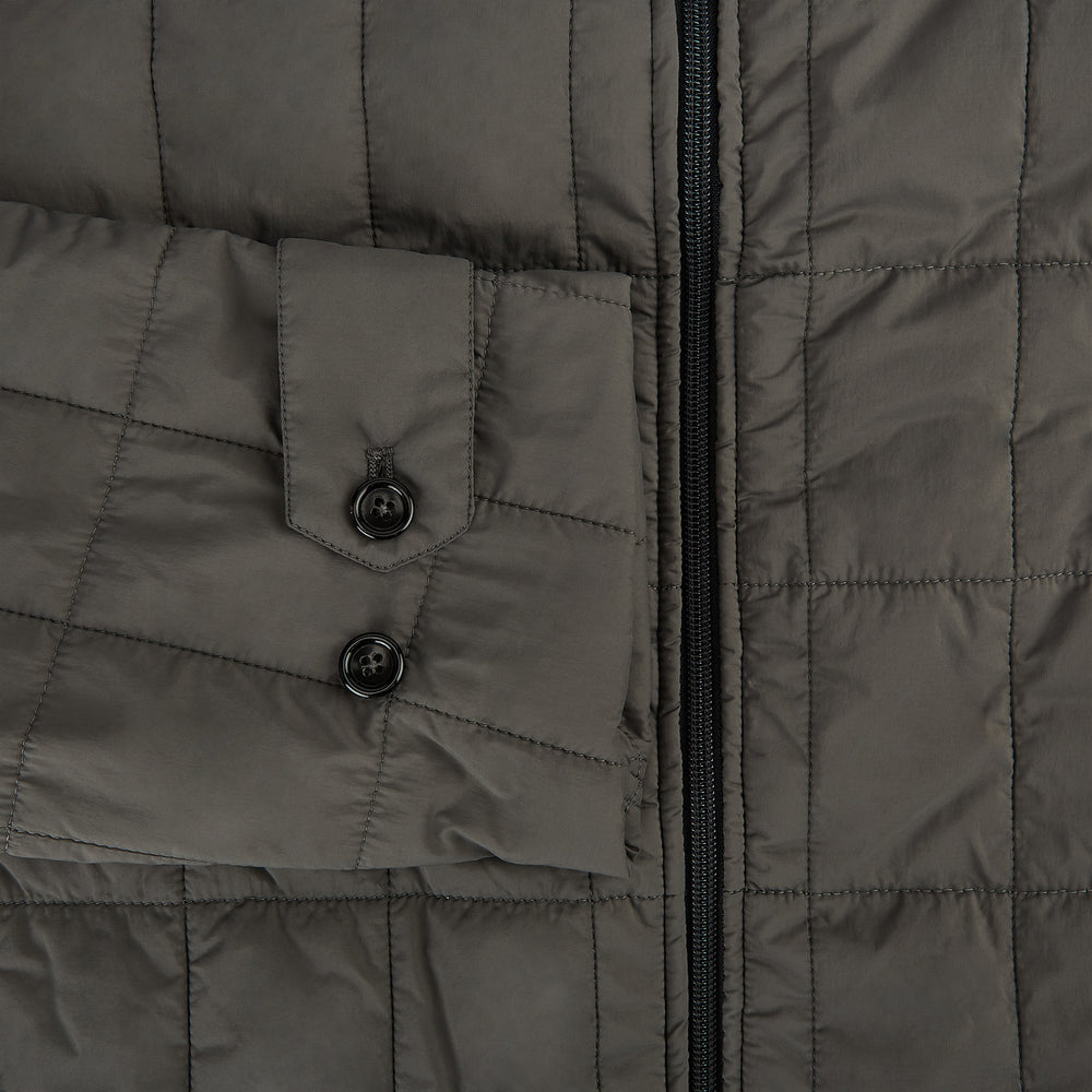 The Battersea Shadow Grey Quilted Jacket by Turnbull & Asser features a front zipper, buttoned cuffs, pointed collar, and multiple pockets—an ideal choice for the modern gentleman. Shown on a plain white background.
