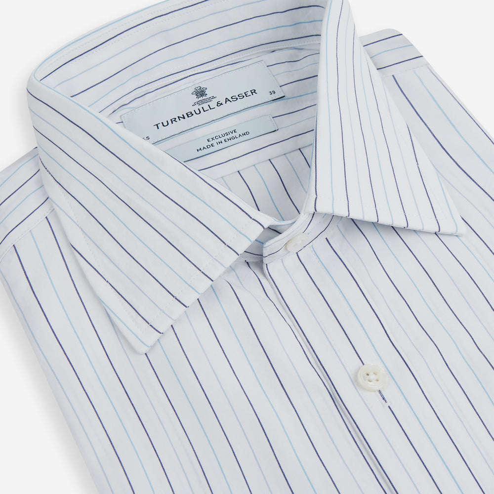 The Turnbull & Asser Blue Wide Pinstripe Mayfair Shirt is a long-sleeved, collared, button-down style crafted from organic cotton, featuring wide blue pinstripes on a white background.