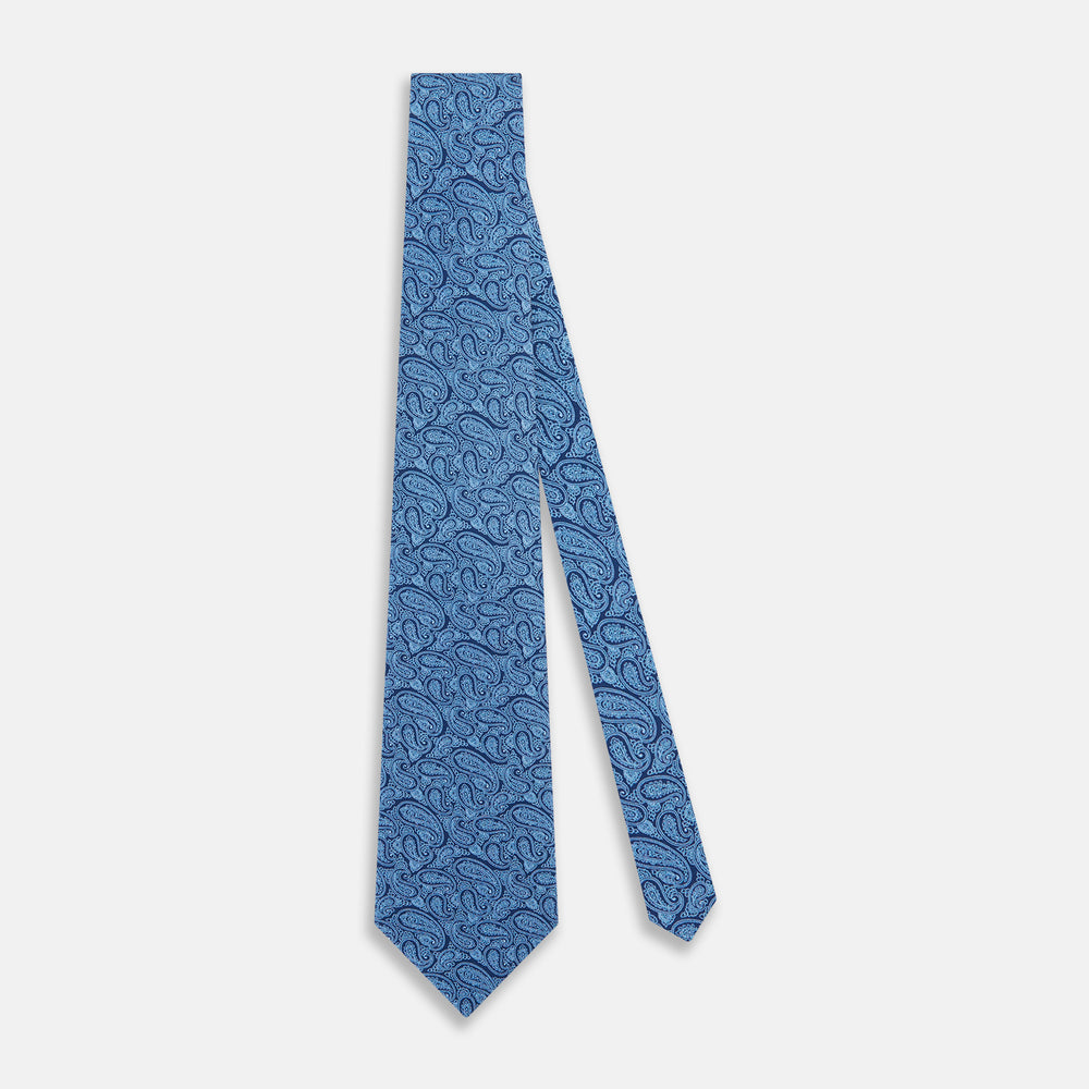 The Turnbull & Asser Azzurro Paisley Silk Tie features an intricate light blue pattern and is crafted from fine English silk—an elegant men's necktie displayed rolled up on a plain white background.