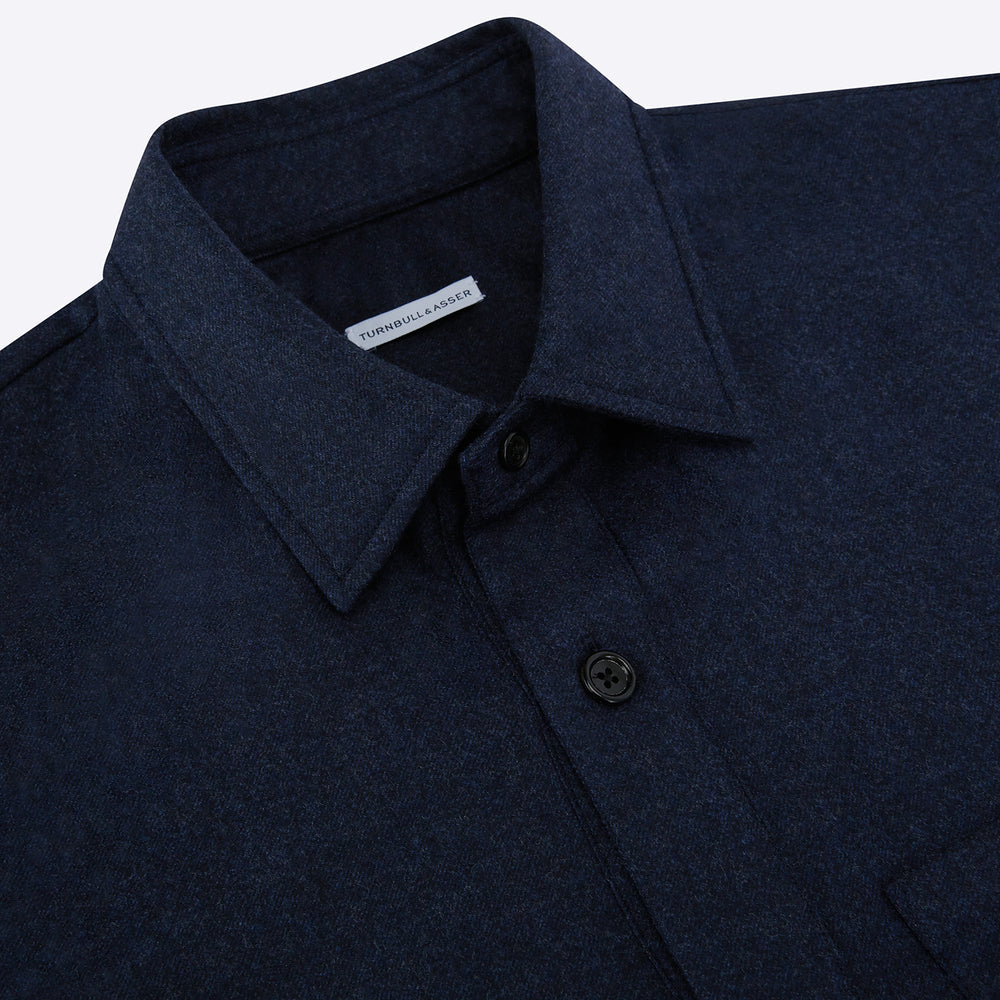 The Turnbull & Asser Mid Blue Highbury Overshirt features long sleeves, a button-up front, collar, and single chest pocket, shown laid flat on a white background.