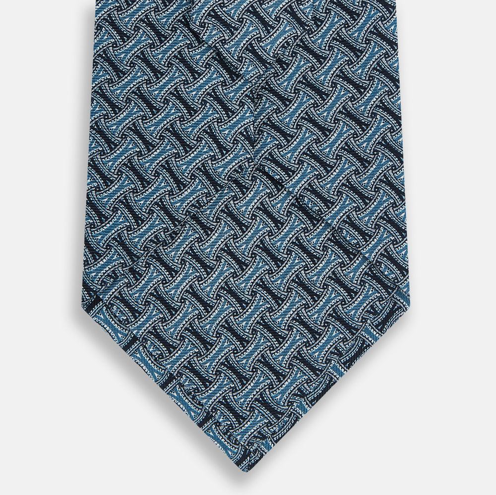 A rolled-up Turnbull & Asser Pale Blue and Navy Weave-Patterned Printed Silk Tie is shown against a white background.