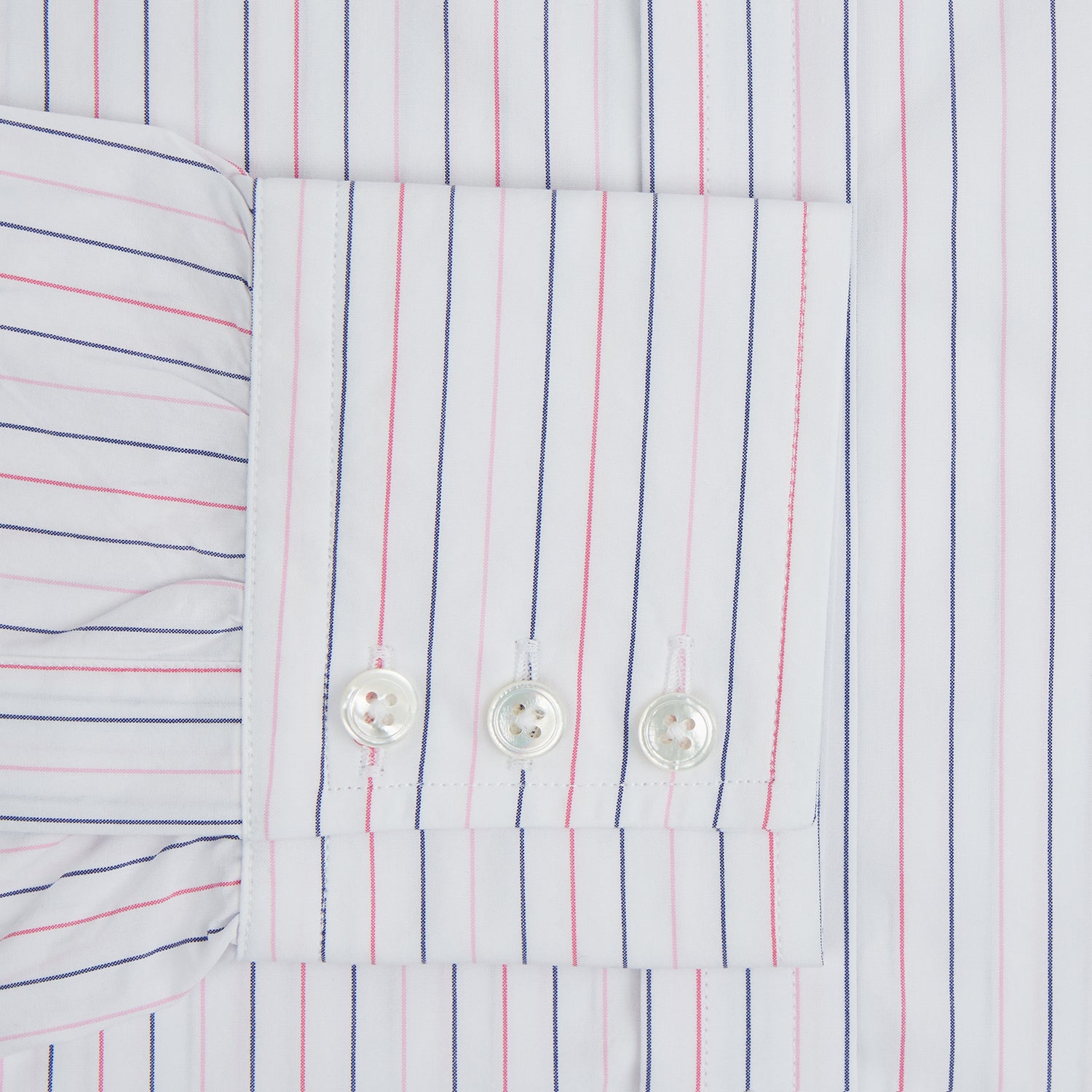 View 11 of product The Turnbull & Asser Pink and Blue Wide Pinstripe Mayfair Shirt features long sleeves, T&A collar, button-down front, and buttoned cuffs. It has bold pink and blue pinstripes on white and is laid flat on a white surface.