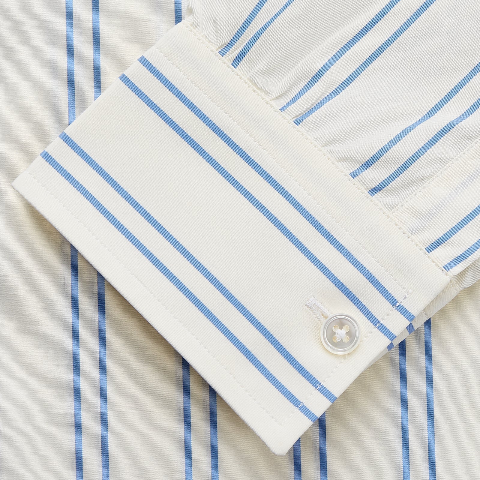 View 4 of product A man with short brown hair stands against a beige background in a Turnbull & Asser Blue and Off-White Stripe Cotton Weekend Fit Finch Shirt, featuring vertical stripes and a Derby collar, paired with dark pants. One hand is in his pocket; he has a neutral expression.