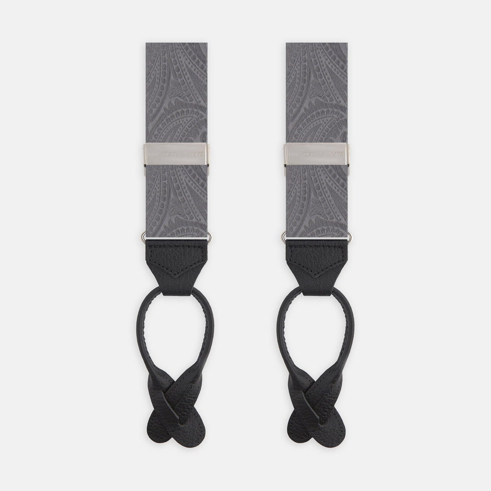 The Turnbull & Asser Silver Paisley Adjustable Silk Braces feature gray paisley silk with silver fittings and black leather ends, offering refined style. The symmetrical braces are displayed flat on a white background.