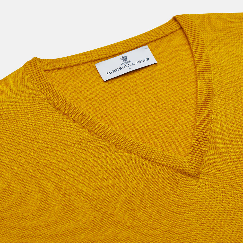 The Gold Paden Cashmere V-Neck Jumper by Turnbull & Asser features a bright yellow hue, long sleeves, ribbed cuffs and hem, and a classic design. It is shown laid flat on a white background.
