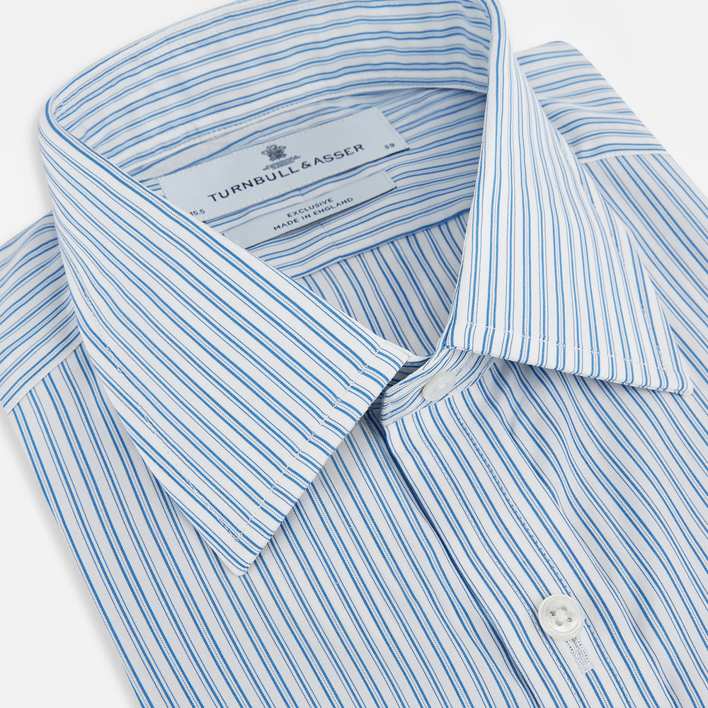 The Turnbull & Asser Sky Blue Double Stripe Mayfair Shirt features sky blue and white vertical stripes, a T&A collar, buttoned cuffs, and is displayed flat on a white background.