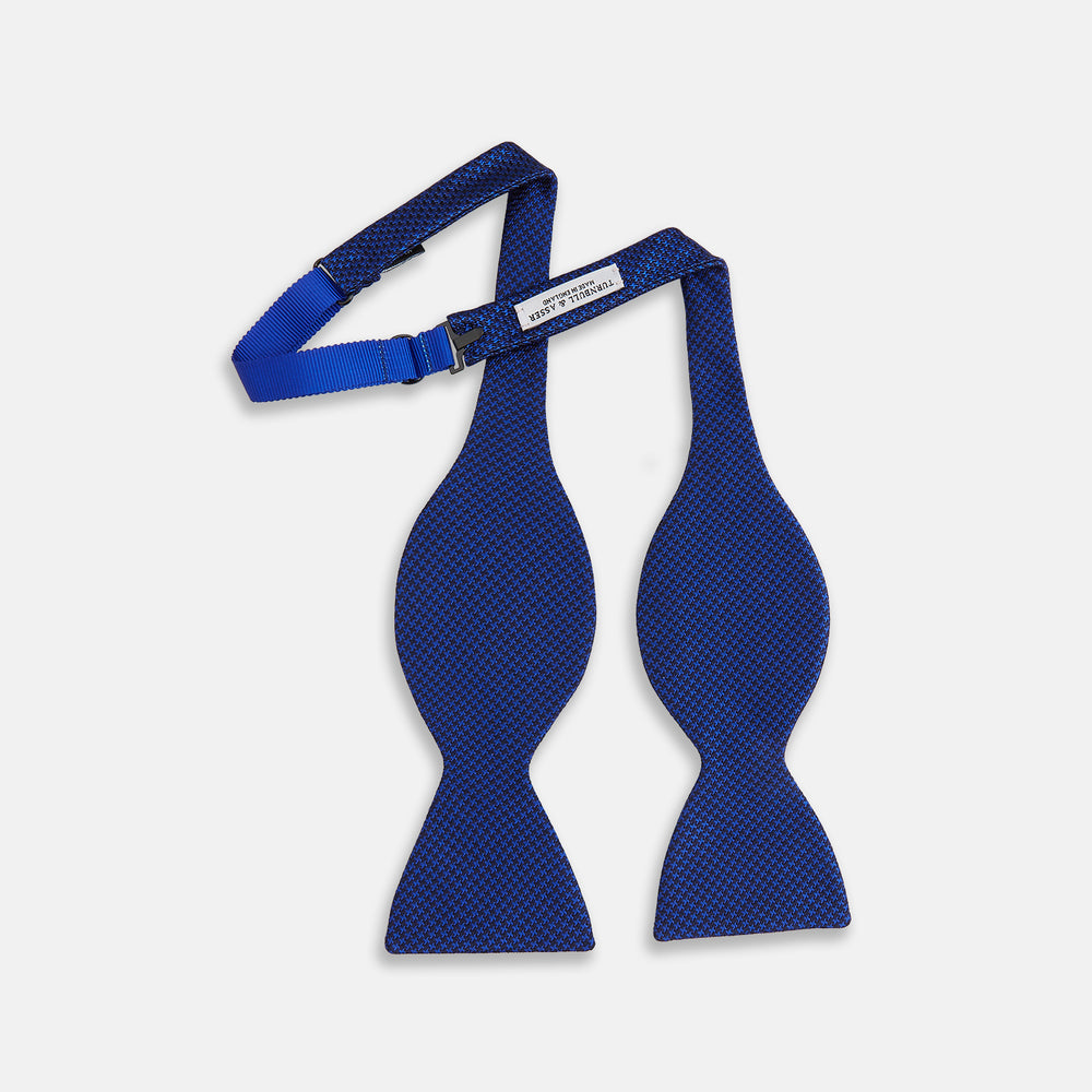 The HOUNDSTOOTH NAVY CRUISE BOW TIE by Turnbull & Asser features a refined textured pattern in blue, neatly tied and set against a white background—a stylish, versatile accessory for the modern gentleman.