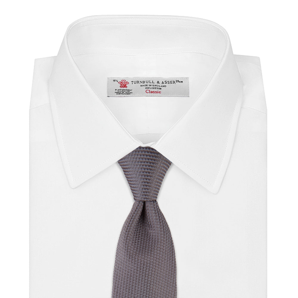 A close-up of the Dark Grey Plain Woven Lace Silk Tie by Turnbull & Asser, neatly rolled and textured, displayed on a light background—an elegant accessory for smart wardrobes.