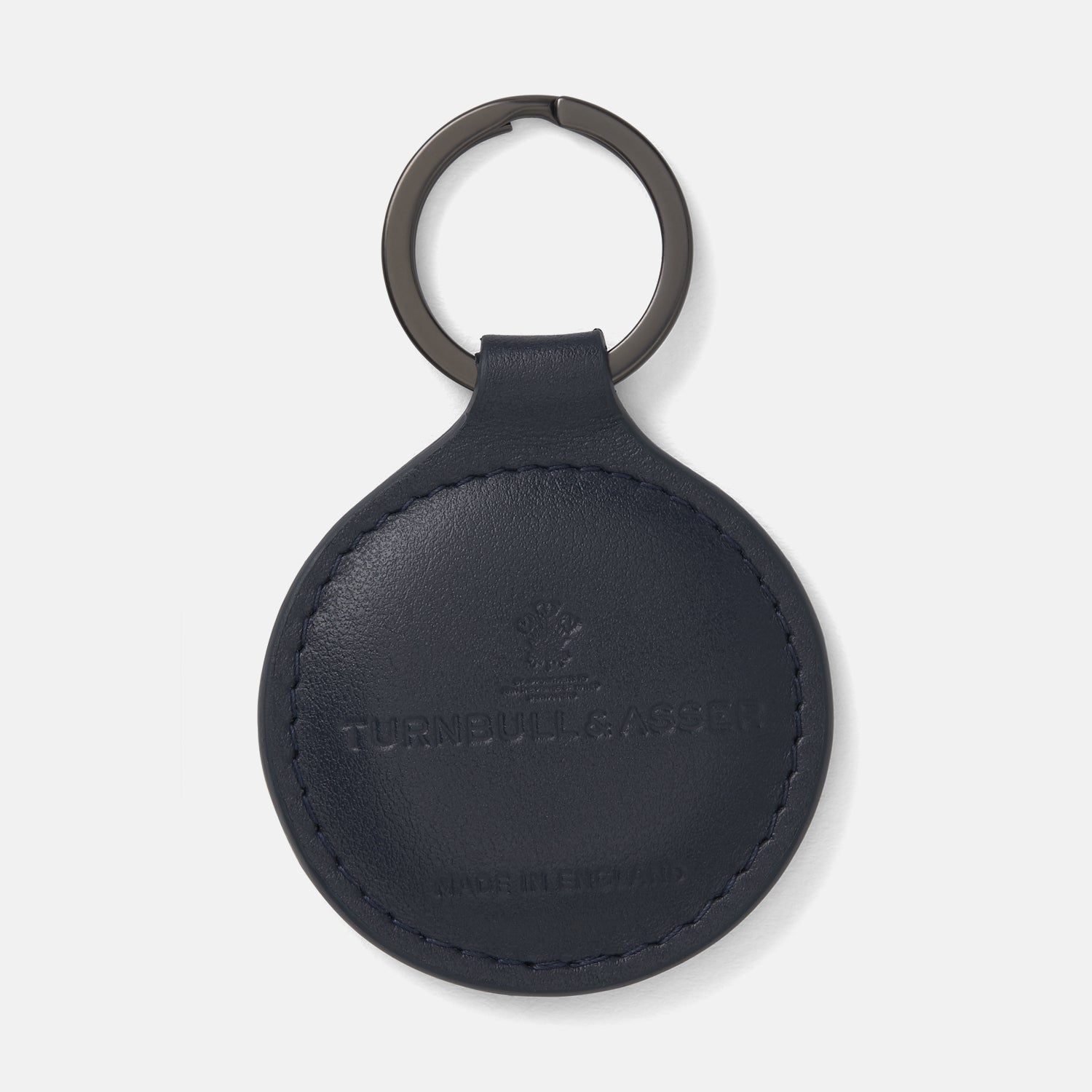 View 1 of product The Dark Navy Leather Fob Holder by Turnbull & Asser features round, dark blue leather with subtle embossed branding and a metallic key ring.