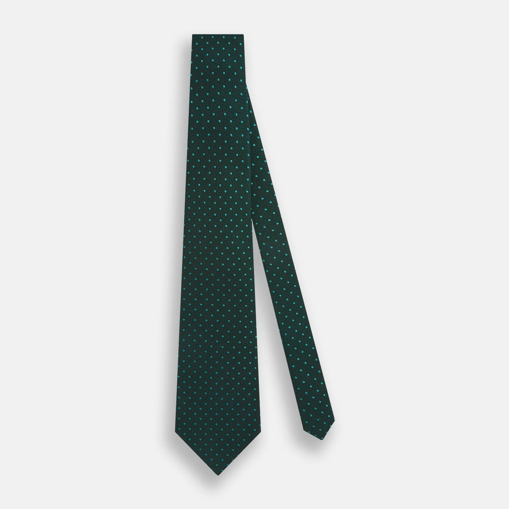 The Turnbull & Asser Dark Green Micro Dot Silk Tie features a refined pattern of light blue micro dots, making it the perfect accessory for any occasion.