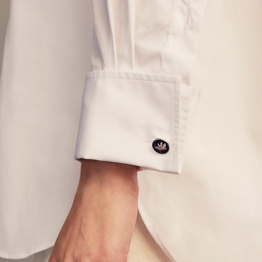A woman with straight brown hair pulled back wears the Turnbull & Asser White Cotton Marlene Shirt, featuring classic menswear details, paired with high-waisted cream trousers against a neutral background.