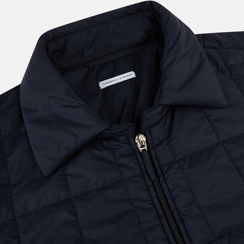 The Turnbull & Asser Battersea Navy Quilted Jacket features a versatile quilted design with a front zipper, zippered pockets, collared neckline, buttoned cuffs, and a subtle square pattern—perfect for the modern gentleman.