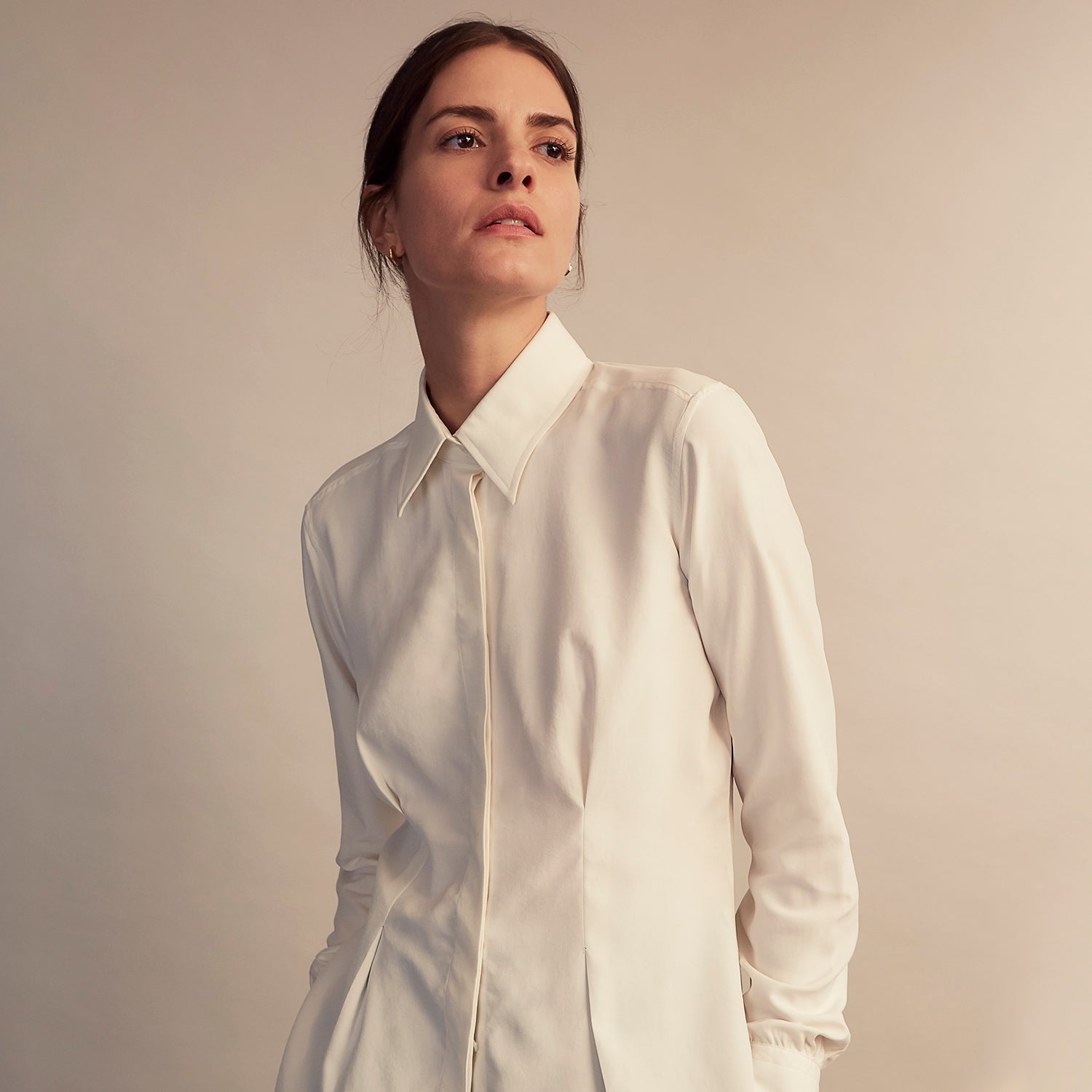View 8 of product The Cream Silk Tailored Bianca Shirt by Turnbull & Asser features long sleeves, a pointed collar, and curved hem in soft-touch peace silk with a tailored fit. Shown laid flat on a white background.