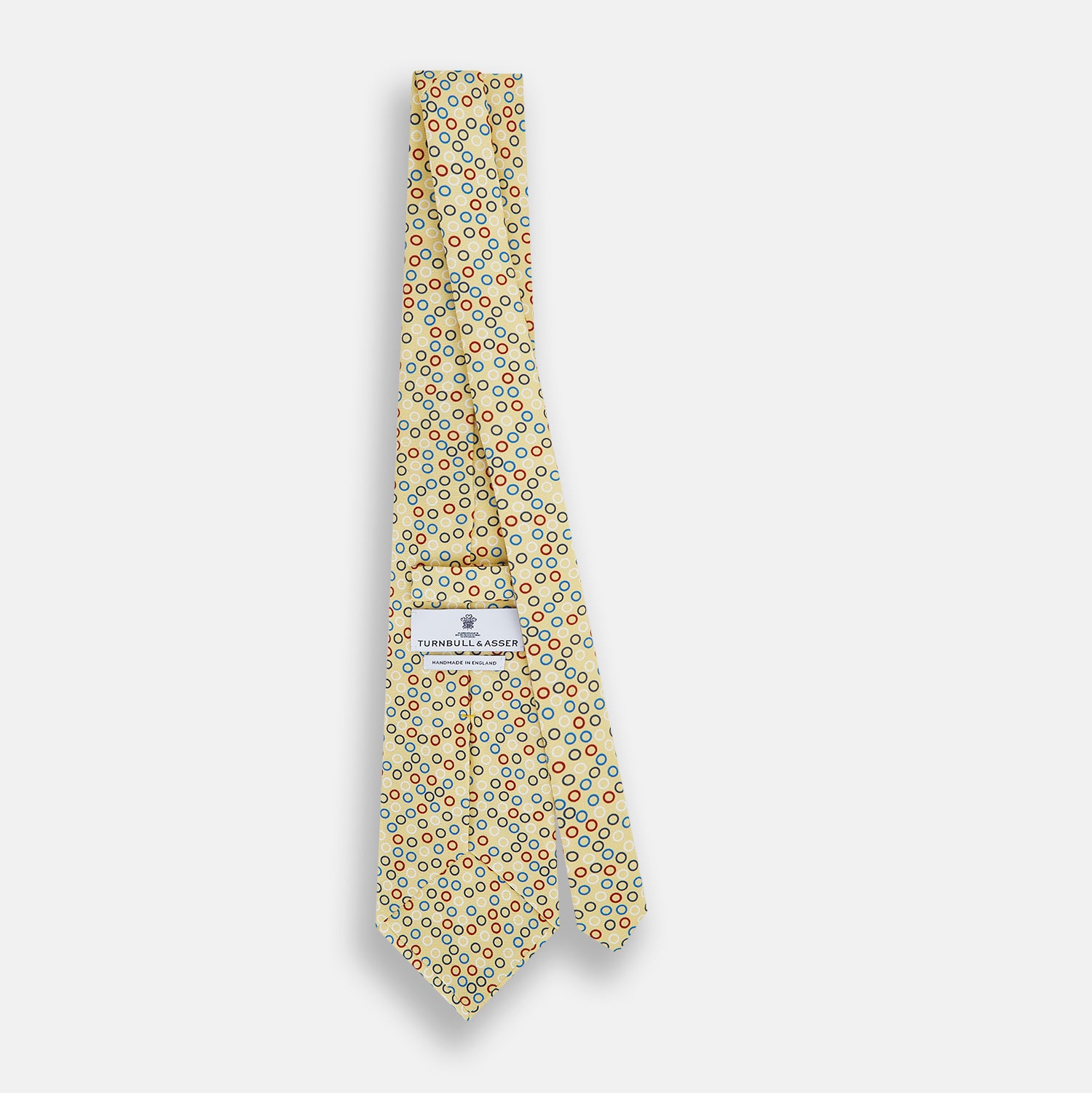 View 4 of product The Turnbull & Asser Multi-coloured Circle Yellow Printed Silk Tie features vibrant blue, red, and black circles evenly spaced across luxurious English silk.