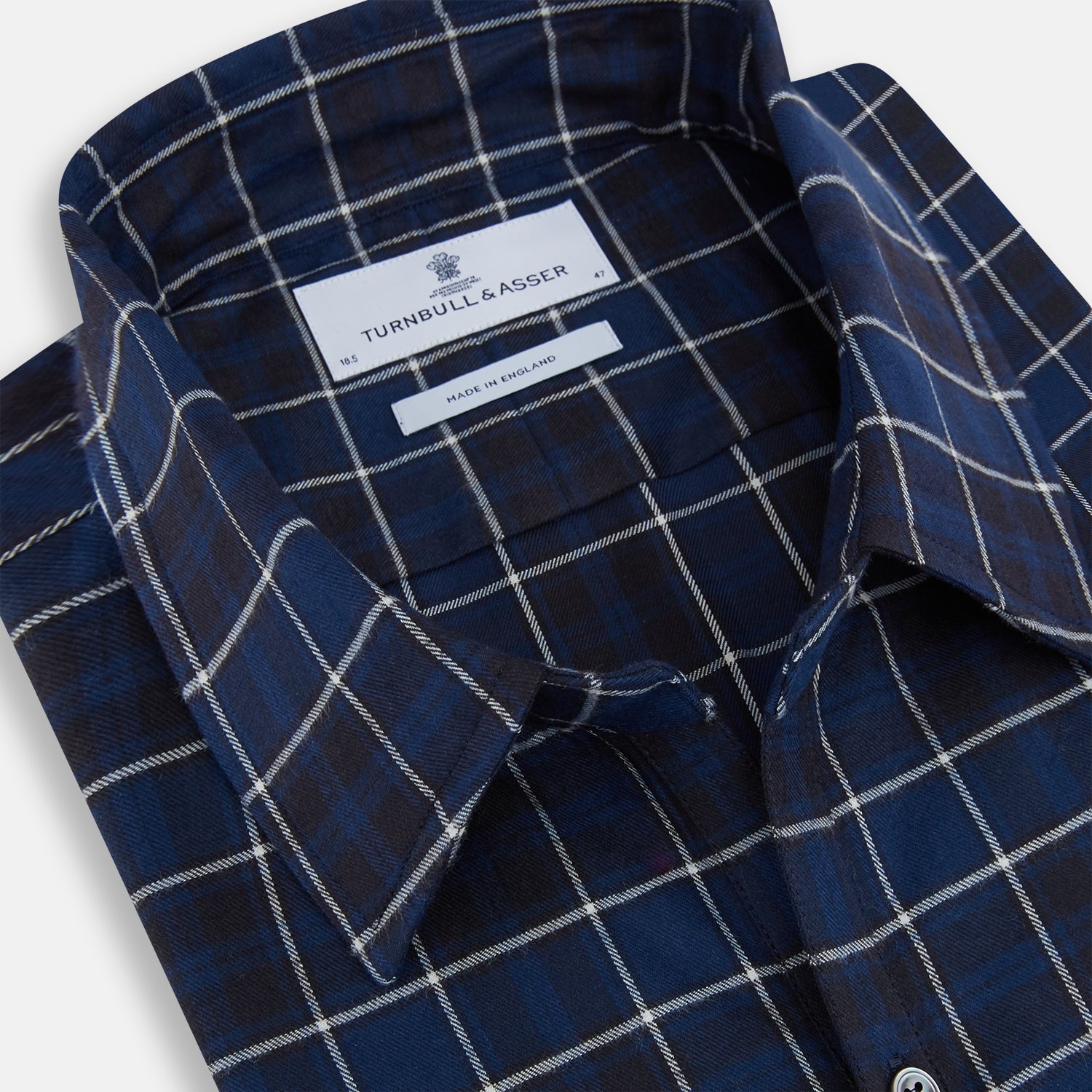 View 2 of product The Turnbull & Asser Navy and White Check Windsor Shirt features a long-sleeve design with a navy base and white check pattern, showcasing British craftsmanship and displayed on a white background.