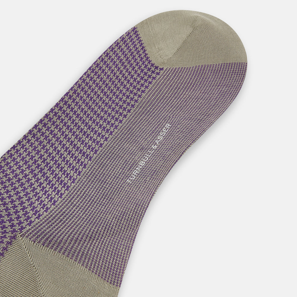 The Turnbull & Asser Concrete Houndstooth Mid-Length Sock features a purple and black houndstooth pattern with beige cuff, heel, and toe, crafted from soft cotton and shown on a plain white background.