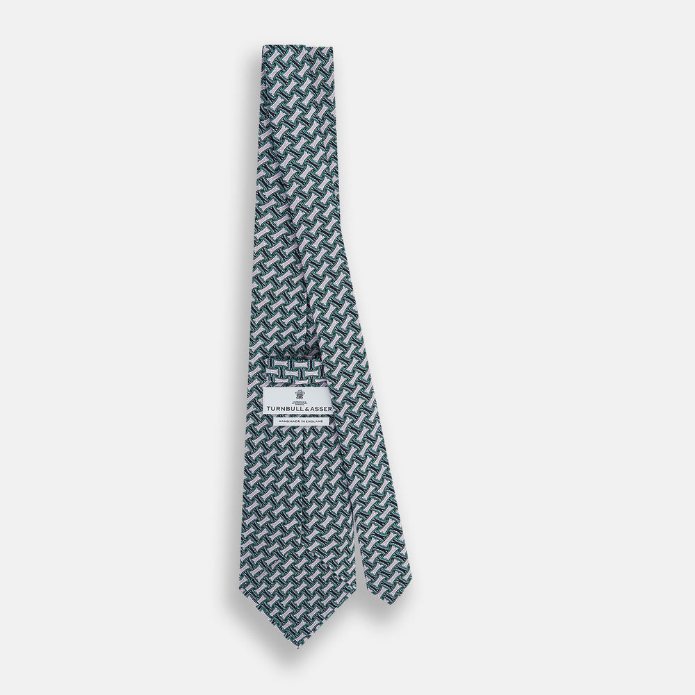 The Turnbull & Asser Lilac and Kelly Weave-Patterned Printed Silk Tie features an elegant geometric design in green, white, and pink on a white background, crafted from English silk with a textured look and classic pointed end.