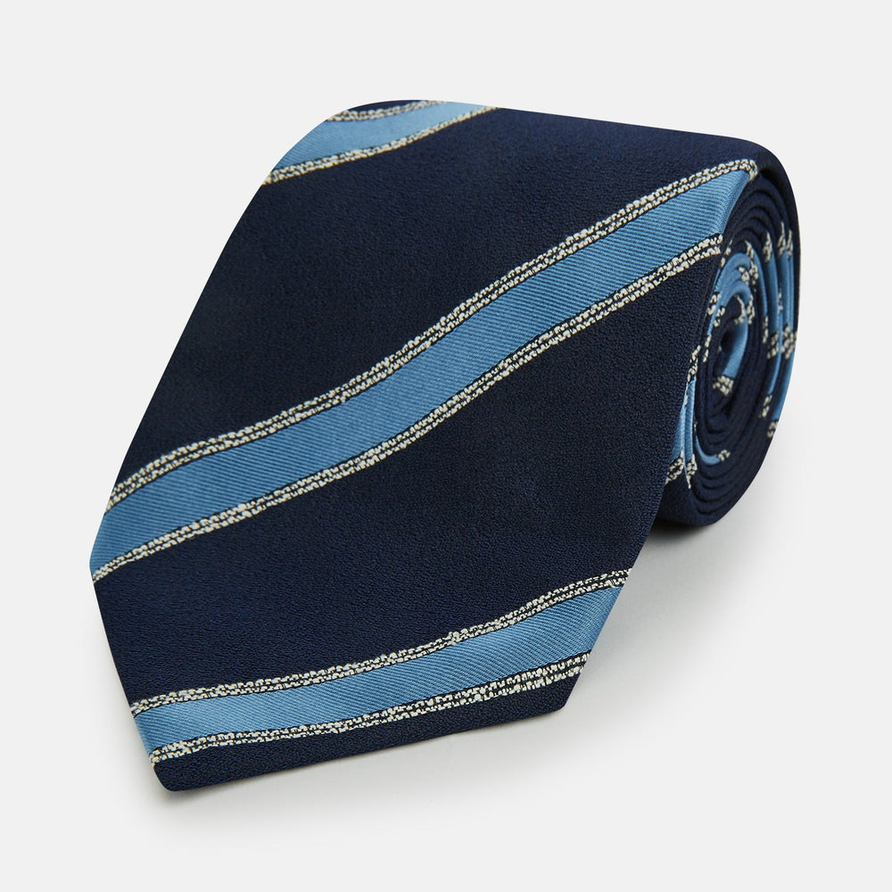 The Turnbull & Asser Navy Multi Stripe Silk Tie features diagonal light blue and silver stripes on an English silk navy base, rolled neatly against a white background.