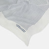 View 2 of product The White Stripe Silk Pocket Square by Turnbull & Asser features vertical navy pinstripes and “TURNBULL & ASSER HAND PRINTED IN ENGLAND” in blue at the lower right, with one corner neatly folded for a classic British look.