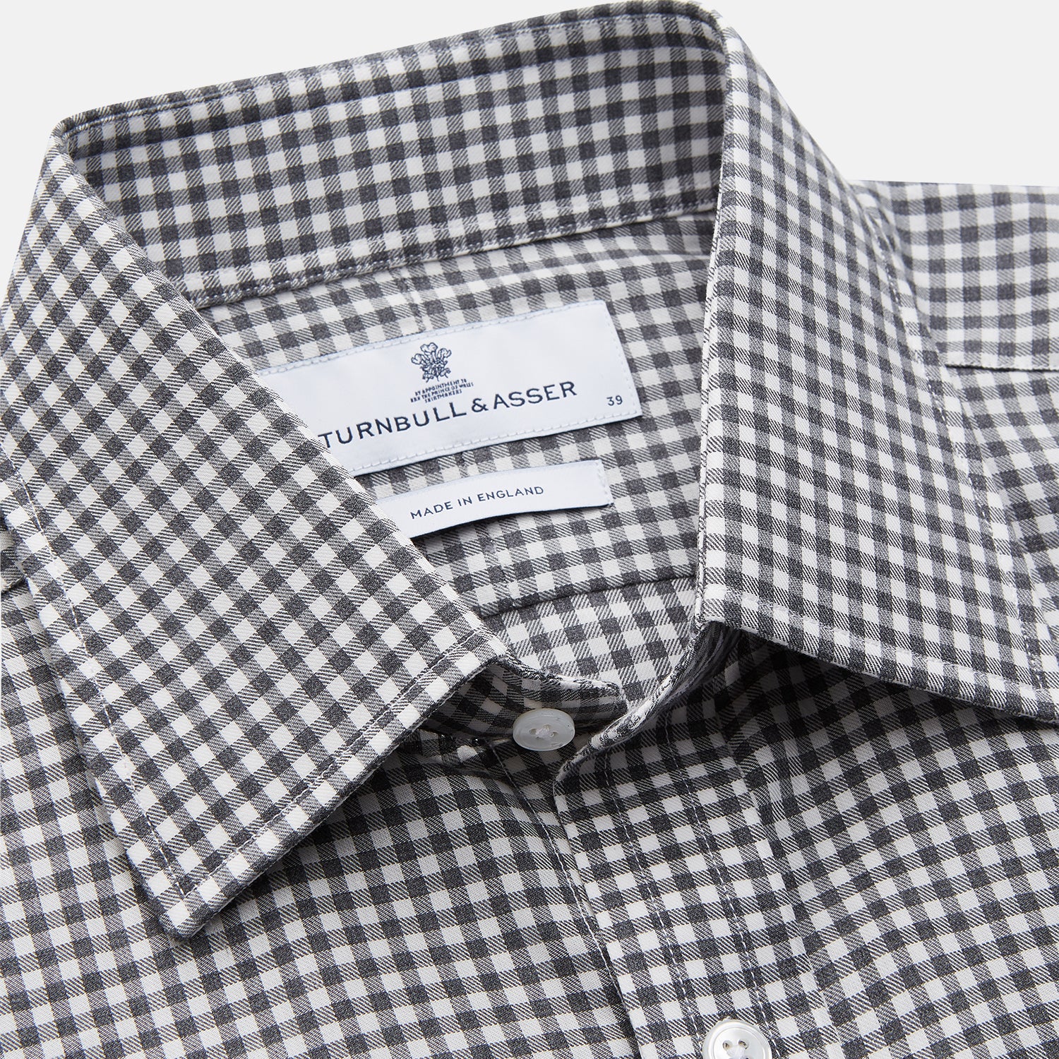 View 2 of product The Turnbull & Asser Grey Gingham Check Cotton Melange Regular Fit Mayfair Shirt, shown flat against a white background, offers a classic designer look with its small black and white check pattern and button-down design.