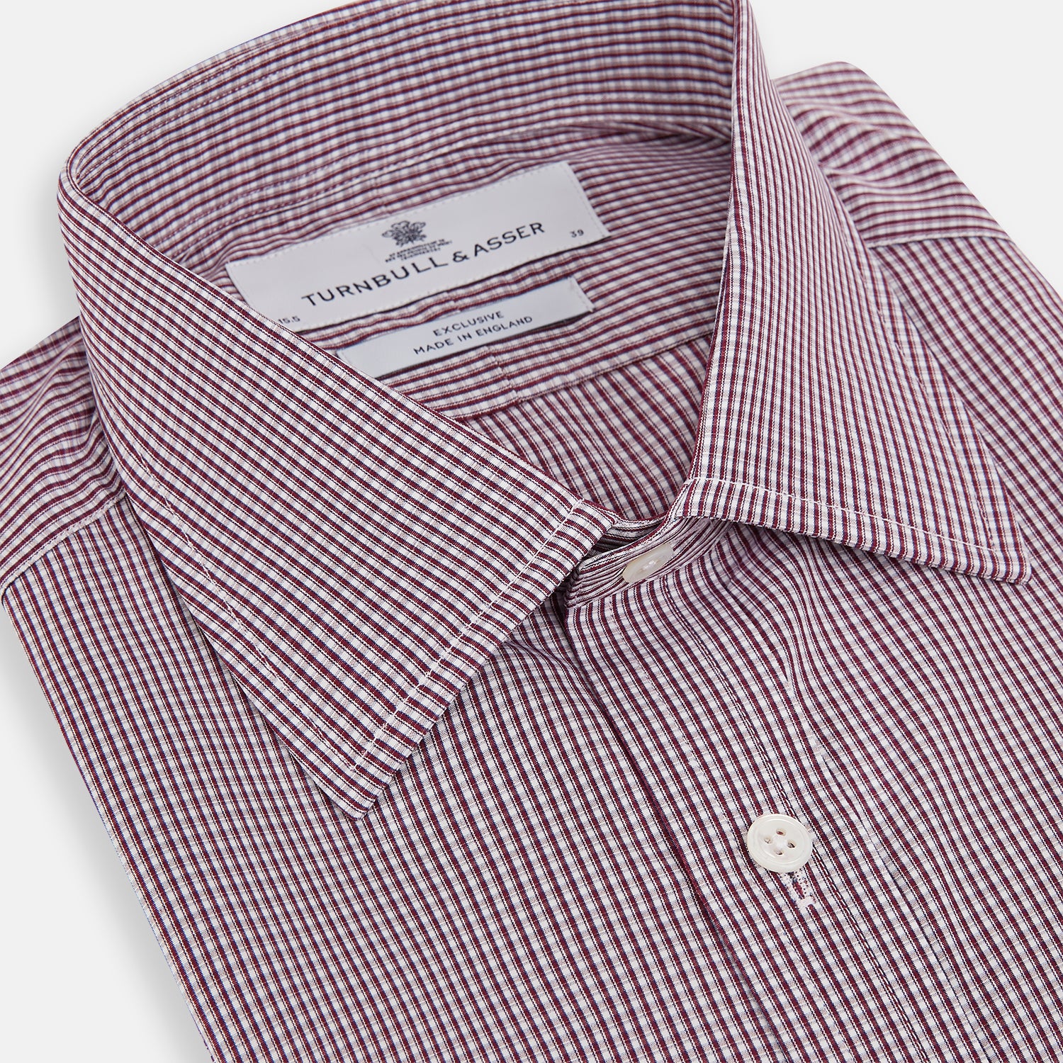 View 2 of product The Turnbull & Asser Burgundy Micro Check Mayfair Shirt features long sleeves, a pointed collar, and white buttons—perfect for formal wear. Shown laid flat on a white background.