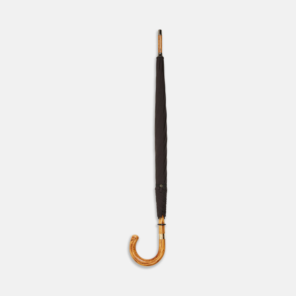 A Black Telescopic Umbrella by Turnbull & Asser with a curved maple handle and shaft, open and angled against a plain white background.