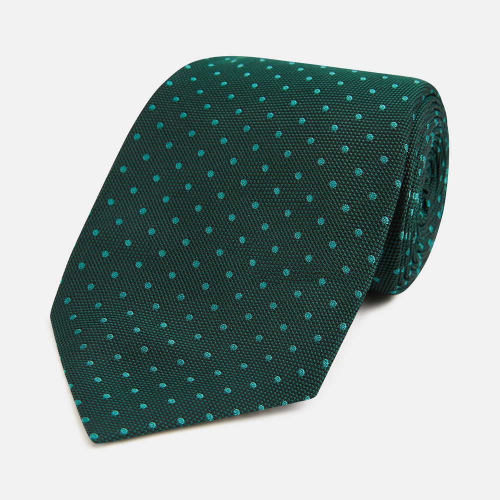 The Turnbull & Asser Dark Green Micro Dot Silk Tie features a refined pattern of light blue micro dots, making it the perfect accessory for any occasion.