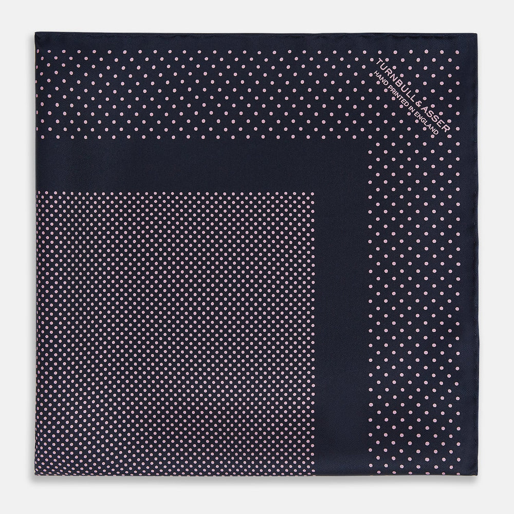 The Turnbull & Asser Navy and Pink Dot Silk Pocket Square features small pink dots and a solid border, with one corner folded to display both sides—an elegant accessory that reflects fine handmade craftsmanship.